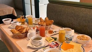 Aamiainen tarjoillaan buffetpöydästä, jossa on monenlaista ruokaa ja juomaa, ja pöytä on sijoitettu ruokailutilaan.