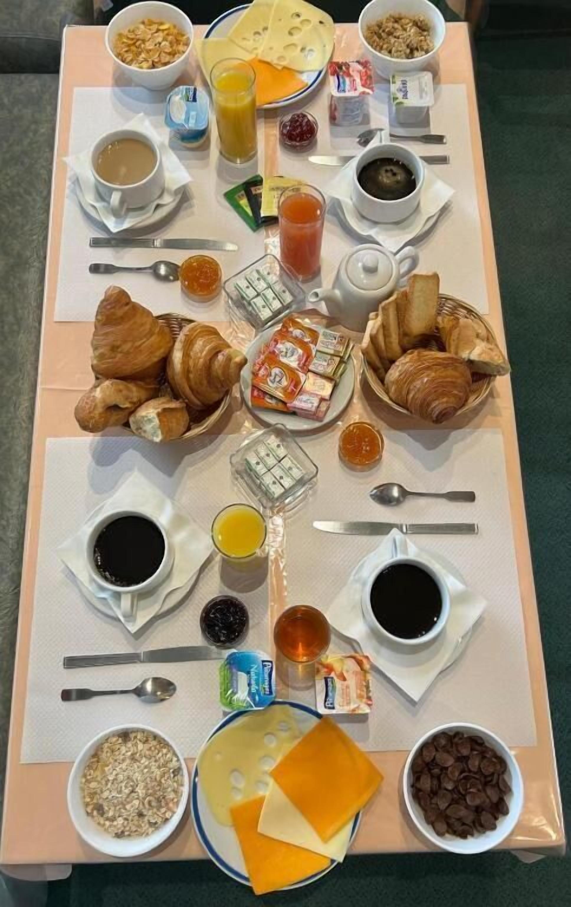 A breakfast tray with croissants, cheese, cereal, juice, coffee, and chocolate chips.