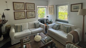 Un salon avec deux canapés blancs, une table basse et des œuvres d’art encadrées accrochées aux murs.