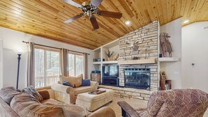 A cozy living room with a stone fireplace, wooden ceiling, and comfortable seating. - Fire Pit + Yard: Woodsy Retreat Near Woodland Lake (Pinetop)