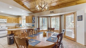 A spacious kitchen with wooden cabinets, a central island, and a dining area with a round table and chairs. - Fire Pit + Yard: Woodsy Retreat Near Woodland Lake (Pinetop)