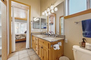 Une salle de bain avec des meubles en bois, un double vasque et des toilettes.