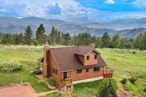 Ein eingeschossiges Holzhaus mit geneigtem Dach, einer Veranda und einer kleinen Terrasse.