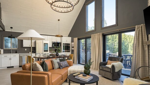 A spacious living area with a modern kitchen, large windows, and a cozy seating arrangement. - Luxe Mtn Cabin | Hot Tub, Sauna, Stargazing Dome (Bailey)