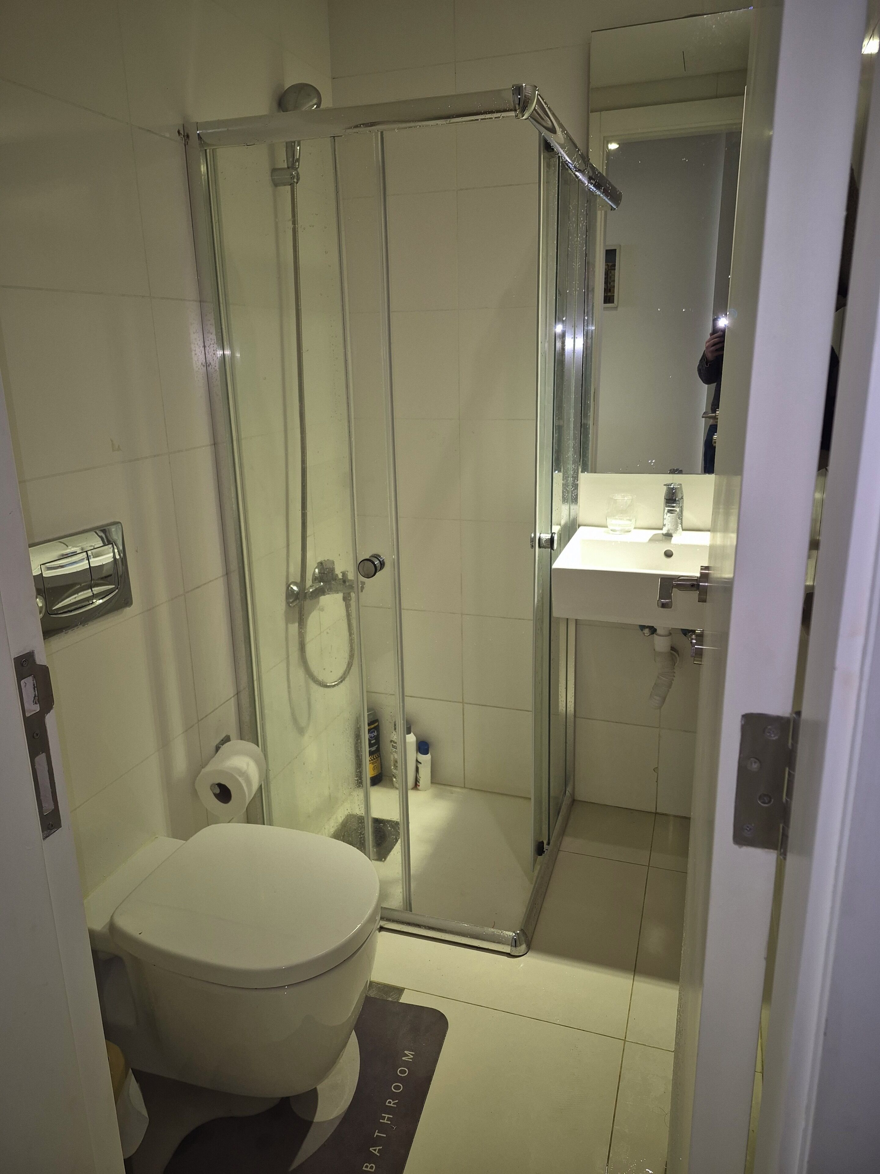 A modern bathroom with a glass-enclosed shower, a toilet, and a sink with a mirror above it.