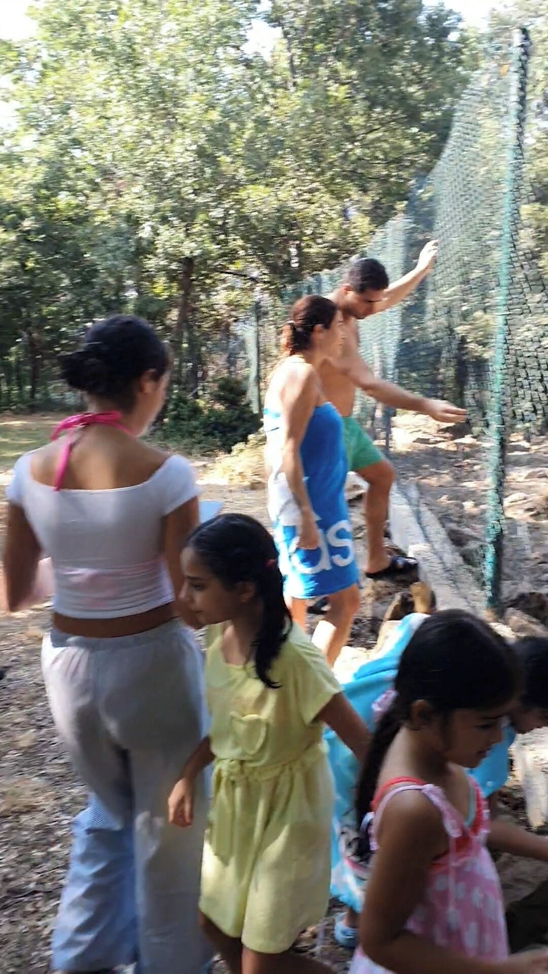 A group of people near a fence in an outdoor setting.