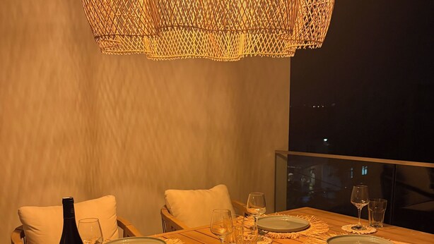 A dining table set for four with plates, glasses, and a bottle, surrounded by chairs with cushions. - TROPICA BLISS (Grand Baie)