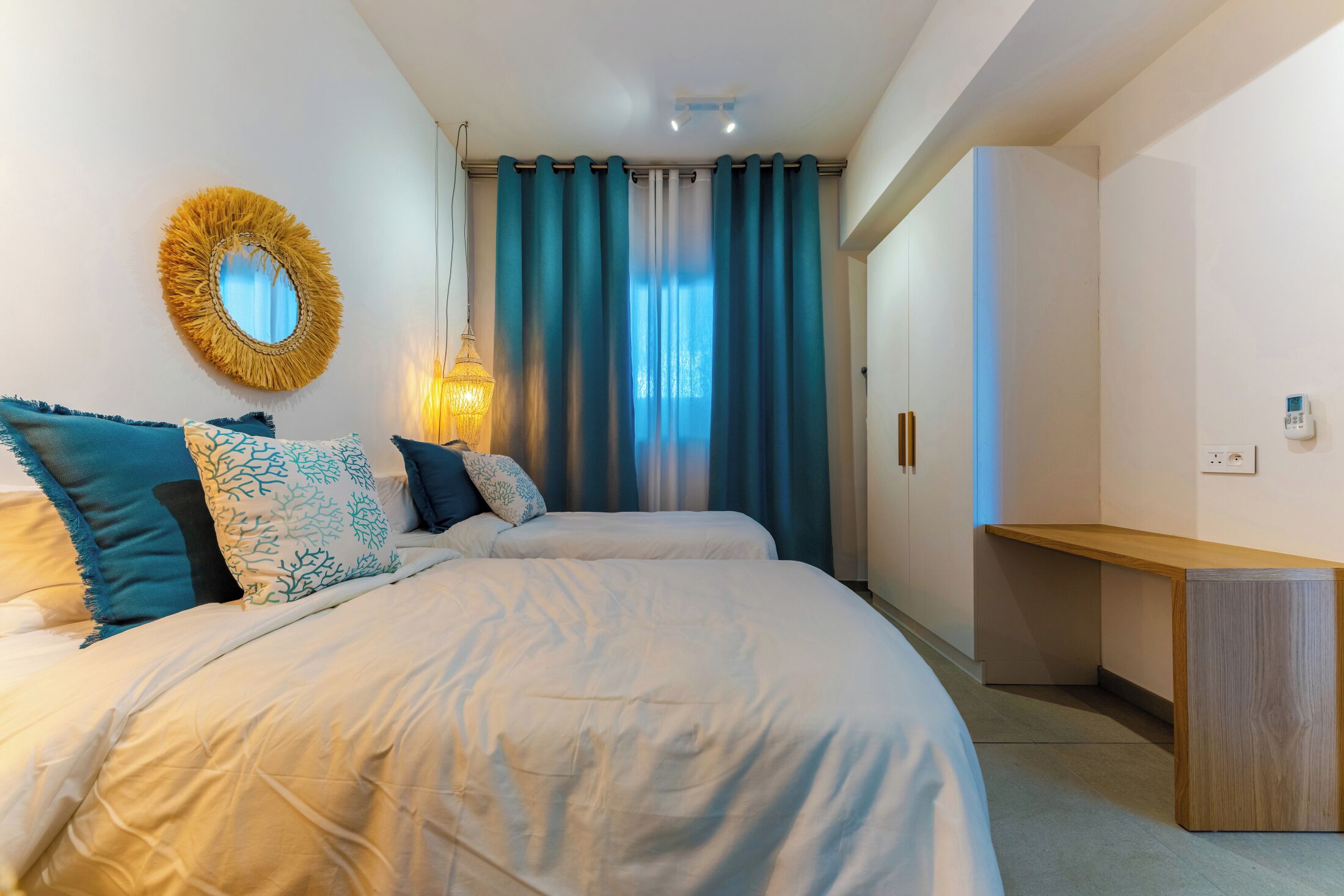 Une chambre à coucher avec un lit, une table de chevet, un miroir, des rideaux et une lampe.