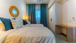 A bedroom with a bed, a bedside table, a mirror, curtains, and a lamp. - TROPICA BLISS (Grand Baie)