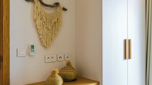 A room with a wooden console table, a macrame wall hanging, and a white wardrobe with two doors. - TROPICA BLISS (Grand Baie)