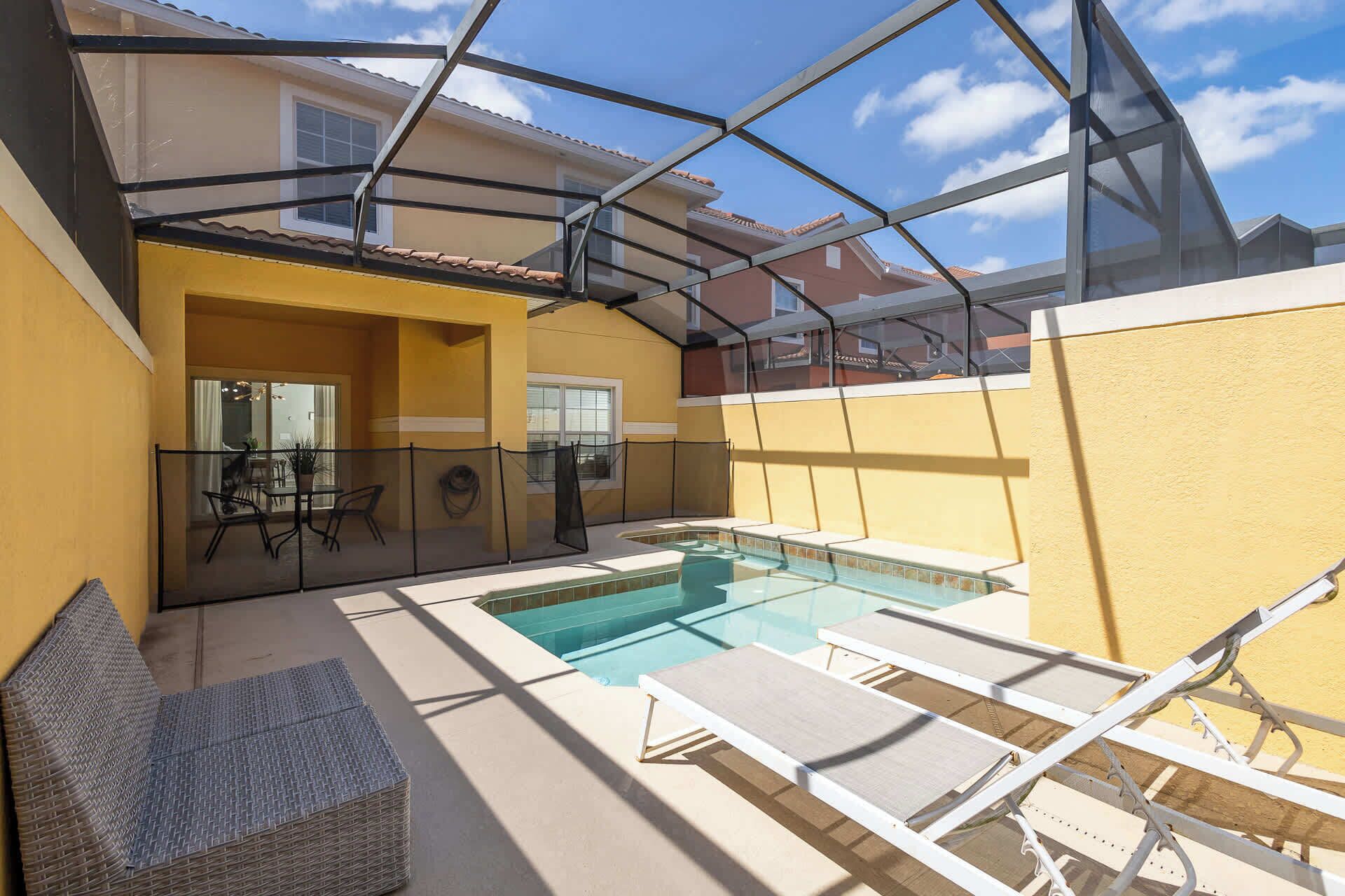 A pool area with lounge chairs and a glass-enclosed patio.