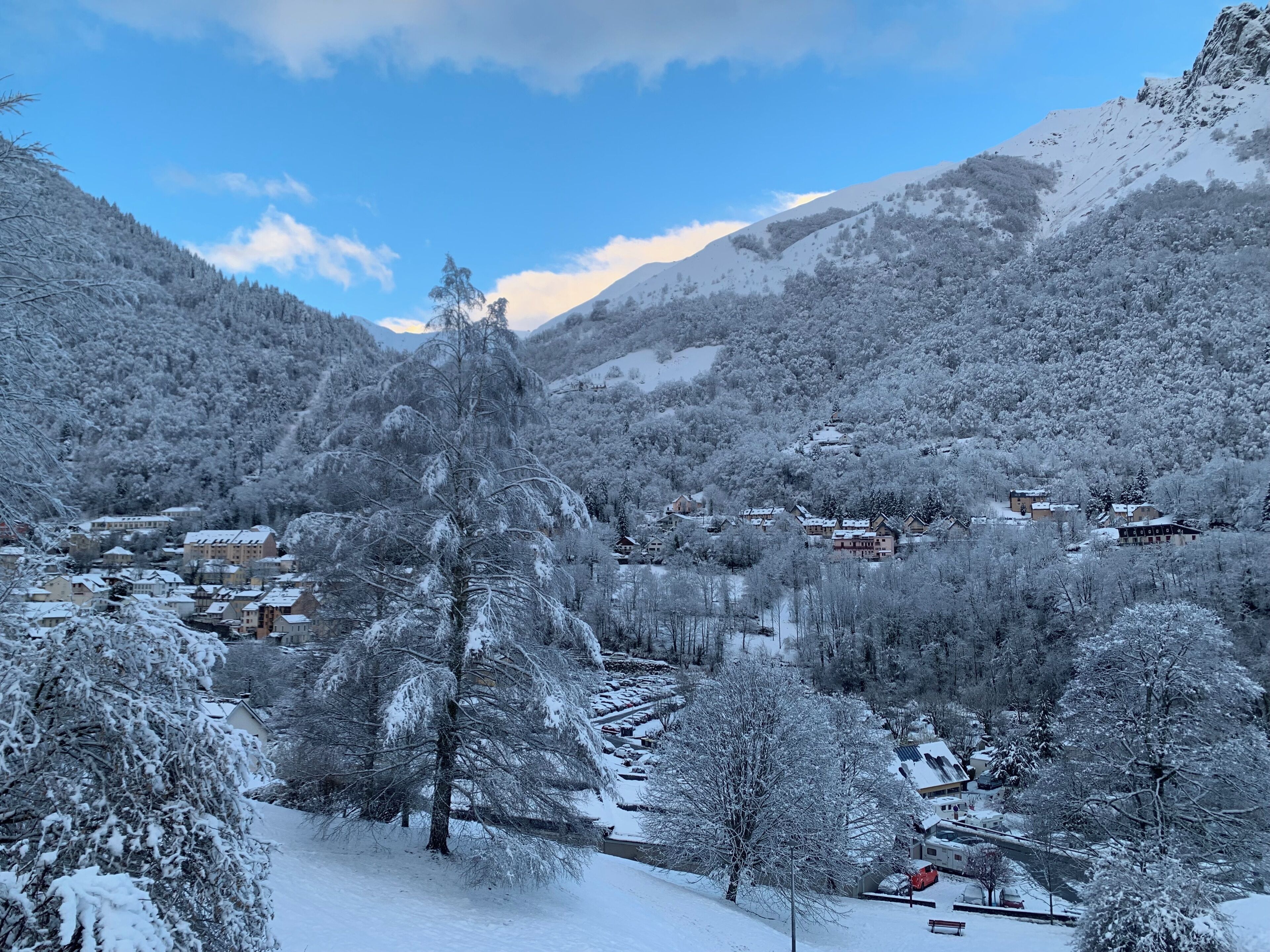 Un pueblo cubierto de nieve con casas y árboles, rodeado de montañas.