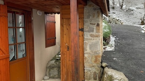 A wooden building with a stone wall, a wooden door, and a window with shutters. - Apartment T2 Vu mountain 700 meters cable car swimming pool in summer (Cauterets)