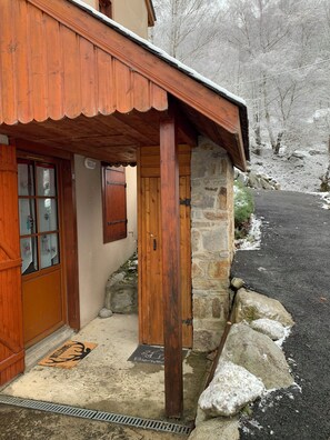 A wooden building with a stone wall, a wooden door, and a window with shutters. - Apartment T2 Vu mountain 700 meters cable car swimming pool in summer (Cauterets)