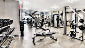 Une salle de sport moderne équipée de divers appareils de musculation, notamment des haltères, des disques de poids et un banc de développé couché.