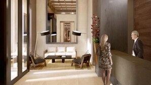 Un espace d’accueil moderne comprenant un canapé, des fauteuils, un comptoir d’accueil et un grand miroir.