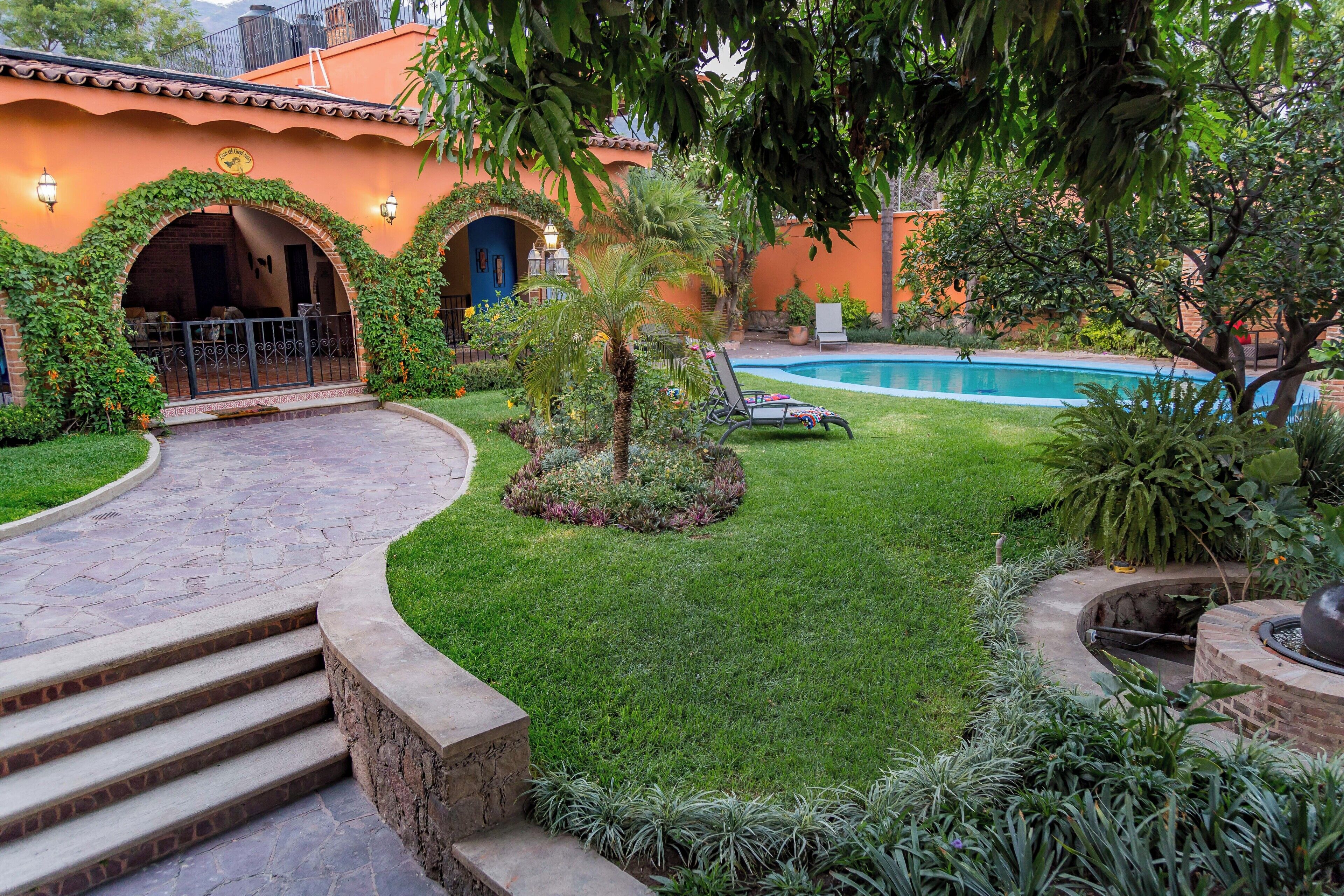 A courtyard with a swimming pool, steps leading to an entrance, and a small tree.