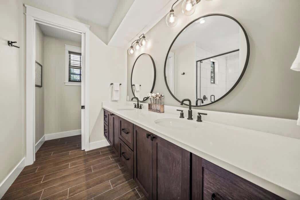 A bathroom with a long vanity, two large mirrors, and a white countertop.