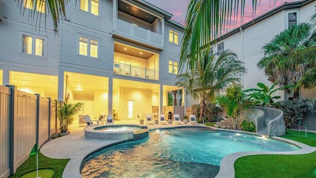 Une maison à deux étages avec une piscine, un espace extérieur aménagé pour se détendre et une pelouse bien entretenue.