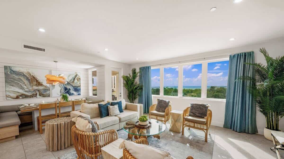 A spacious living room with a large window, a sofa, a coffee table, and various chairs.