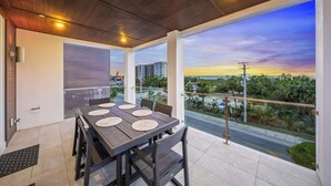 A dining area with a table and chairs, large windows with a view of a cityscape and greenery, and a wooden ceiling. - New - Dual-home luxury, Rooftop Decks, Sleeps 32 (Siesta Key)