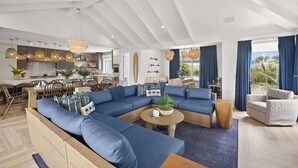 Una sala moderna con un sofá modular, una mesa de centro redonda y un comedor con una mesa y sillas de madera.