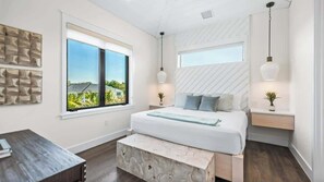 Una camera da letto moderna con un letto grande, due comodini, una panca e una finestra vista verde.