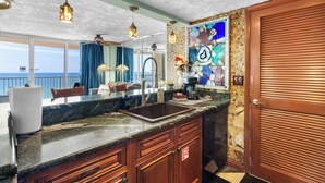 Una cocina con encimera de mármol, armarios de madera, un lavamanos y un salpicadero decorativo.