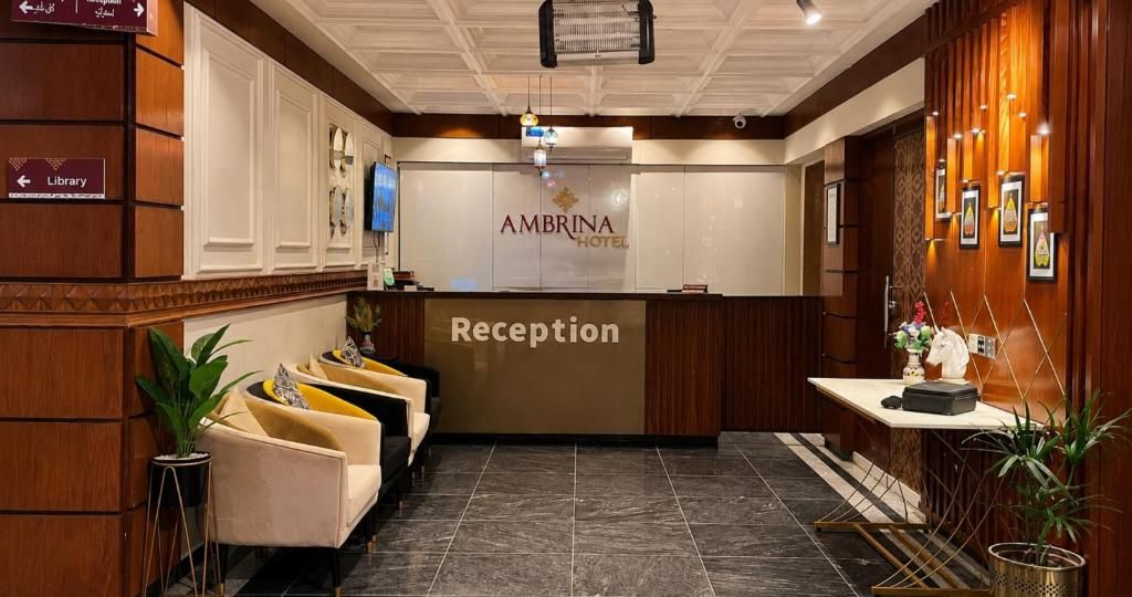 A hotel reception area with a reception desk, a television, and a sign indicating the library.