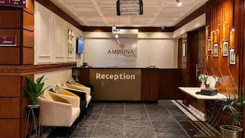 A hotel reception area with a reception desk, a television, and a sign indicating the library.