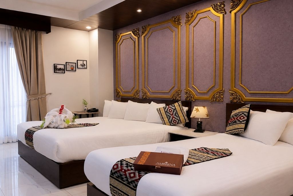 A hotel room with two beds, a nightstand, a lamp, and a decorative wall panel.