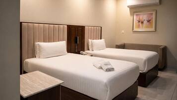 Habitación de hotel con dos camas, una mesita de noche y un cuadro en la pared.
