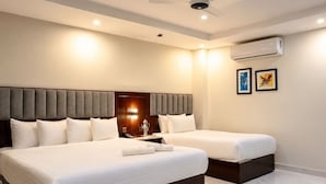 Een hotelkamer met twee bedden, een plafondventilator, een airconditioning en kunst aan de muur.
