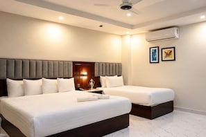 Habitación de hotel con dos camas, ventilador de techo, aire acondicionado y una obra de arte en la pared.