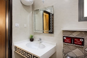 Un baño con lavabo blanco, espejo y un cartel sobre el ahorro de agua.