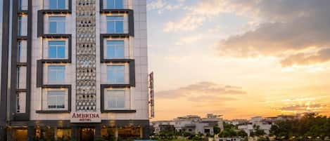 A multi-story hotel with a prominent entrance, a vertical decorative pattern, and a view of the surrounding area.