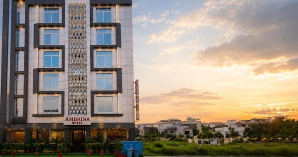 Un hotel de varios pisos con una entrada destacada, un patrón decorativo vertical y vistas del entorno.