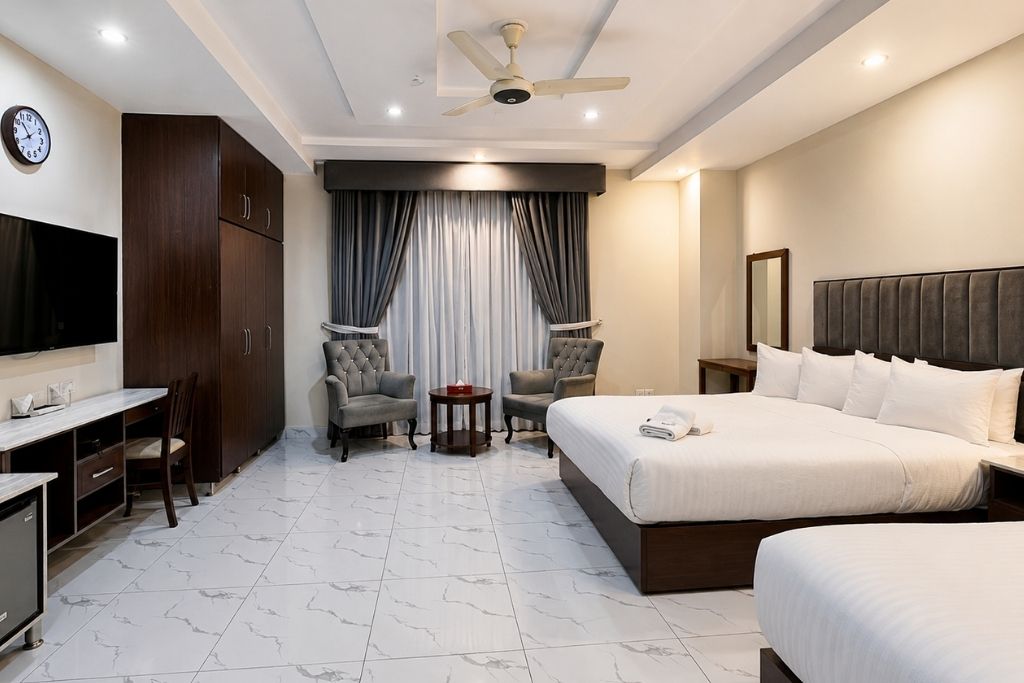 A hotel room with a bed, a desk, a TV, and a ceiling fan.