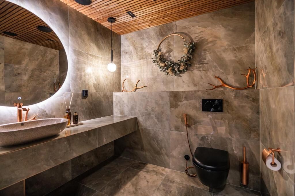 Ein modernes Badezimmer mit einem Steinsink, Holzboden und einem dekorativen Kranz an der Wand.