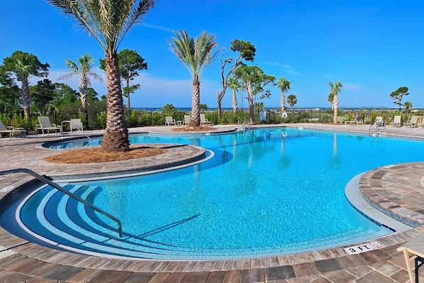 A swimming pool with a clear blue water, surrounded by palm trees and lounge chairs. - Tranquil Coastal Escape - Just Steps to the Beach - Bikes included (Port St. Joe)