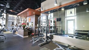 Ett gym med olika typer av träningsutrustning, inklusive löpband, styrketräningsmaskiner och fria vikter.