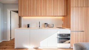 A modern kitchen with white cabinetry, a built-in oven, and a countertop with a coffee maker and toaster. - GuestReady - Maleo Living Apartments - 10C1 (Lisbon)