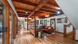 Ein geräumiges Loft mit Holzbalken, einer Küchenzeile und einem Wohnbereich mit Sofa und Esstisch.