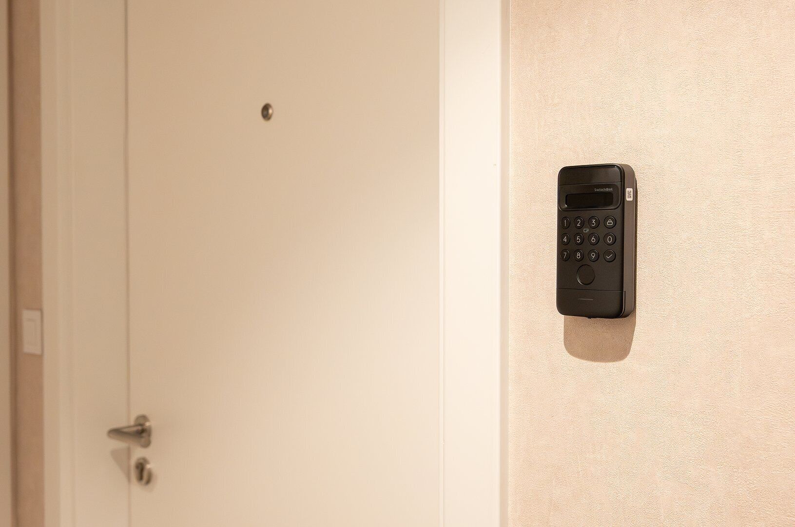 Une porte dotée d’un clavier électronique fixé au mur, probablement pour contrôler l’accès à la pièce ou assurer la sécurité.
