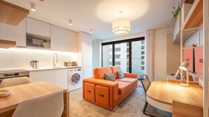 Um apartamento moderno com cozinha, sofá, área de refeições e vista para a cidade.