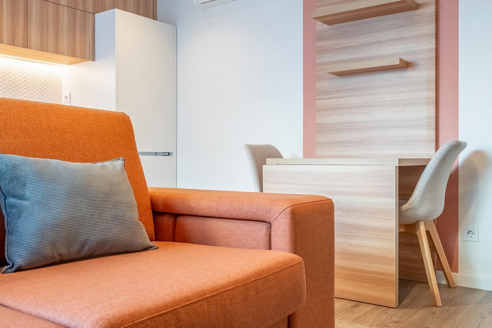 A modern room with a sofa, a wooden desk, and a chair.