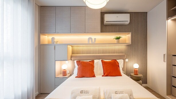 Ein modernes Hotelzimmer mit einem großen Bett, Nachttischlampen, einer integrierten Heizung und einer Minibar.