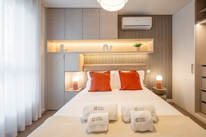 Habitación de hotel moderna con una cama grande, lámparas de noche, calefacción integrada y minibar.