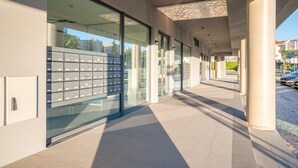 Ein modernes Gebäude mit großen Glasfenstern, einem überdachten Gang und einer Reihe von Briefkästen.