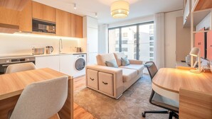 Een modern appartement met kitchenette, een bank, een eethoek en uitzicht op de stad.